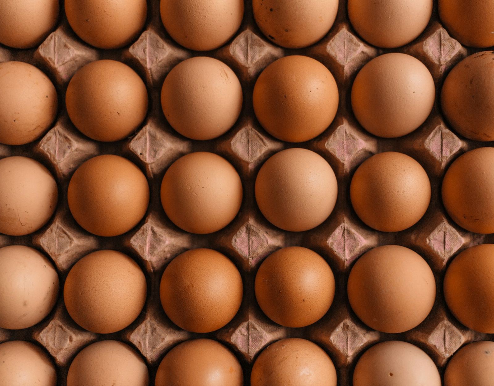 Rows of brown eggs sit in a moulded cardboard tray.